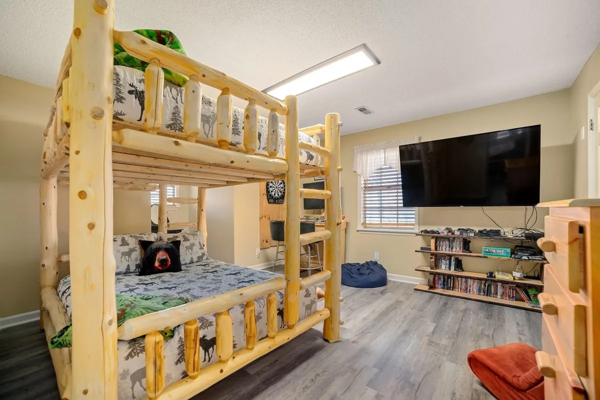 A playful interior space with a bunk bed, bean bag chair, television, and shelves full of books and games. The room is designed for fun and comfort, ideal for family game nights, sleepovers, and creative play.